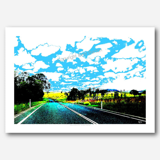 "A country road dips and turns off to the left surrounded by fields and trees and a huge sky."