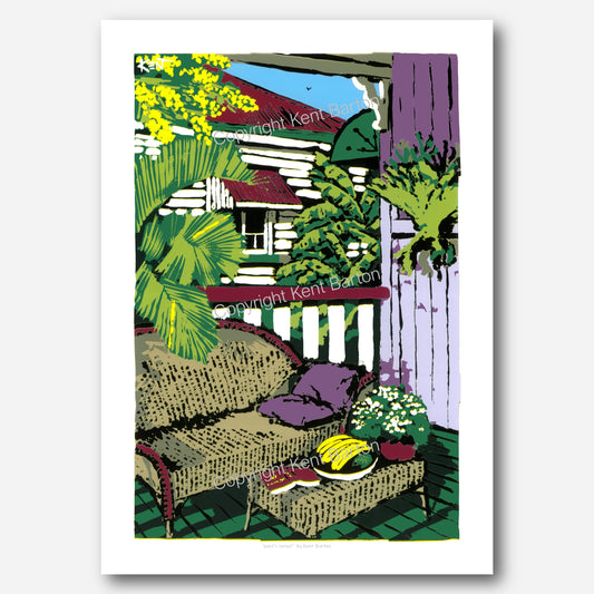 "Cane lounge with pillow and book and bananas on a cottage veranda with view of house next door."